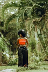 Elegant woman poses in a vibrant tropical garden, showcasing fashion and nature.