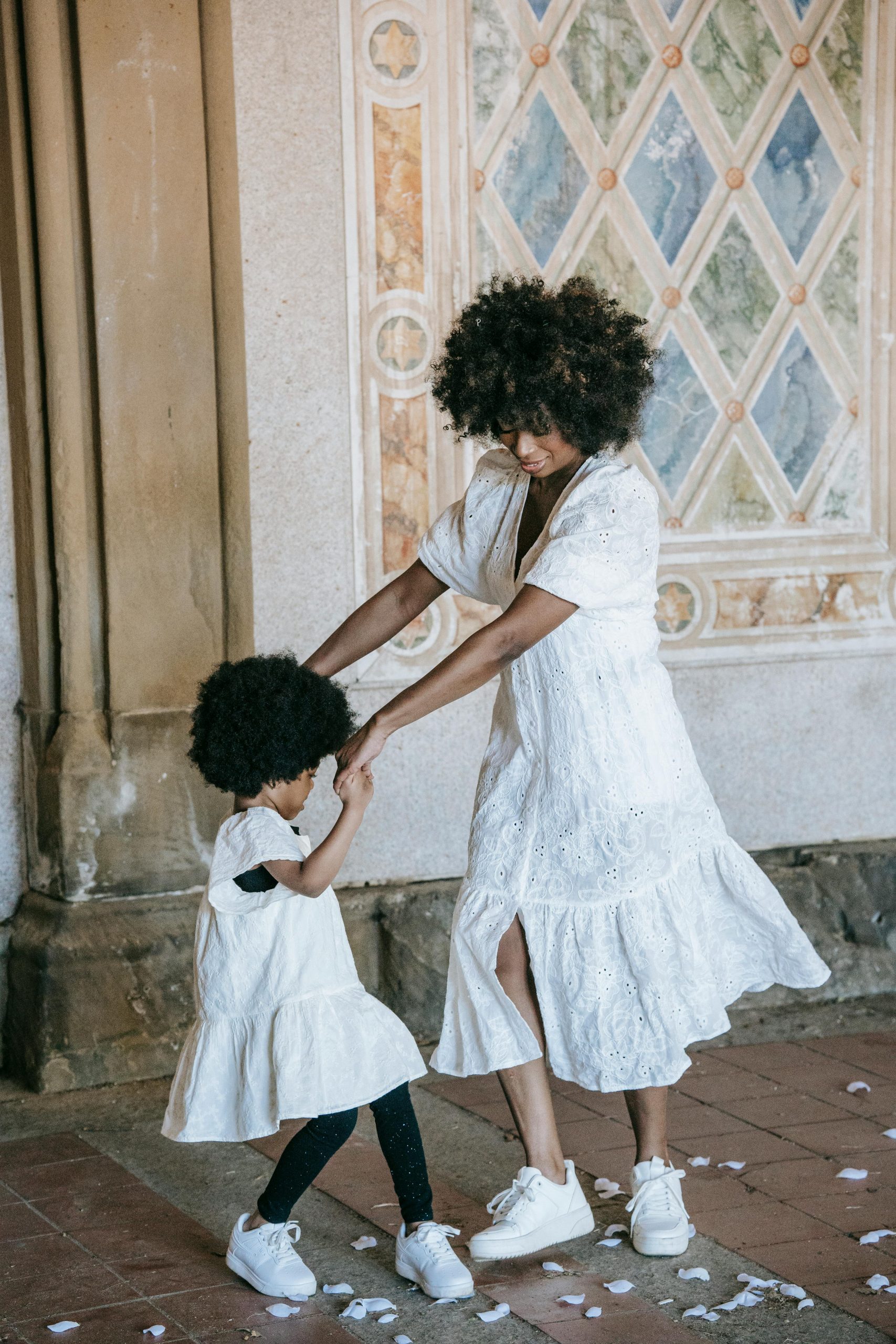 A heartwarming moment of a mother and daughter dancing together in a vintage setting.